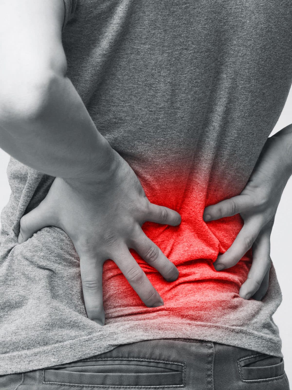 A person clutching their lower back, with the area of pain highlighted in red.
