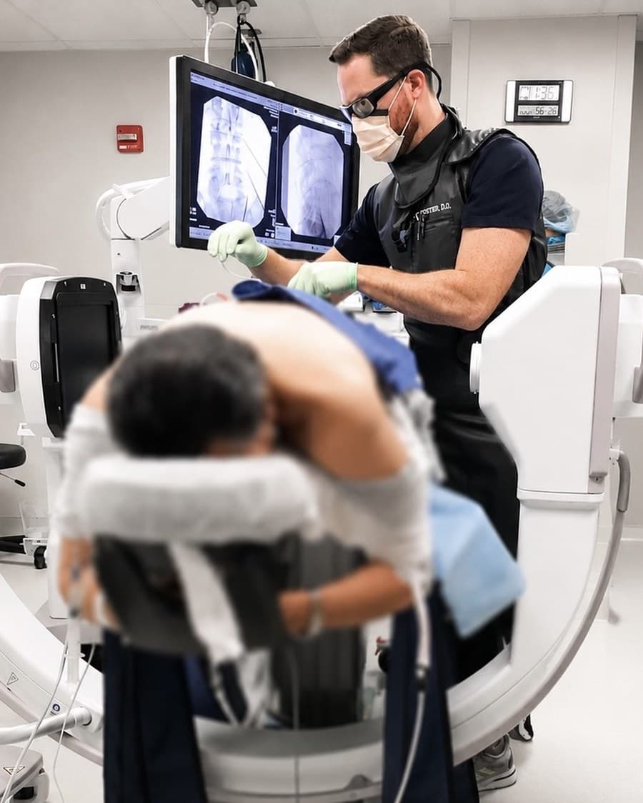 Dr. Foster reviewing dual fluoroscopic X-ray images on a monitor mid-procedure.