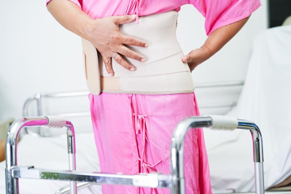 A patient wearing an elastic back support belt while using a walker.